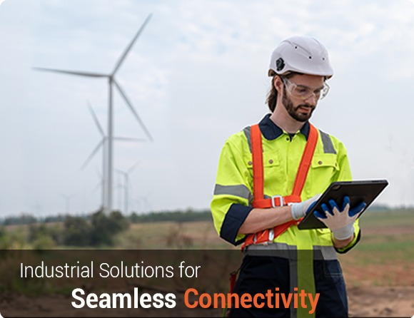 a field engineer working with a IoT dashboard on a tablet device and standing in a field with windmills in the background